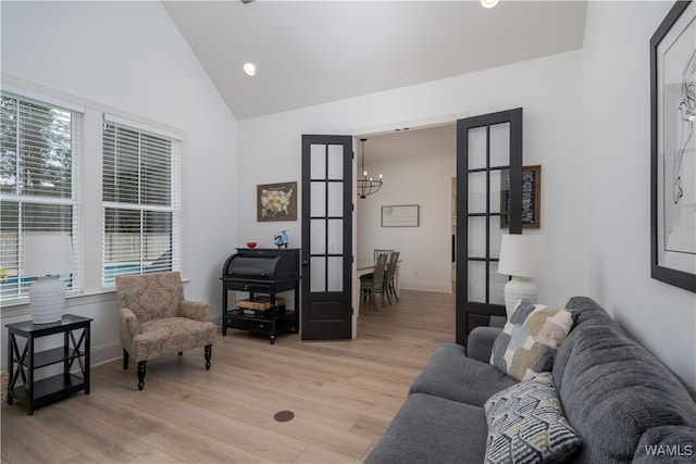 living room with a chandelier, french doors, high vaulted ceiling, and light hardwood / wood-style flooring