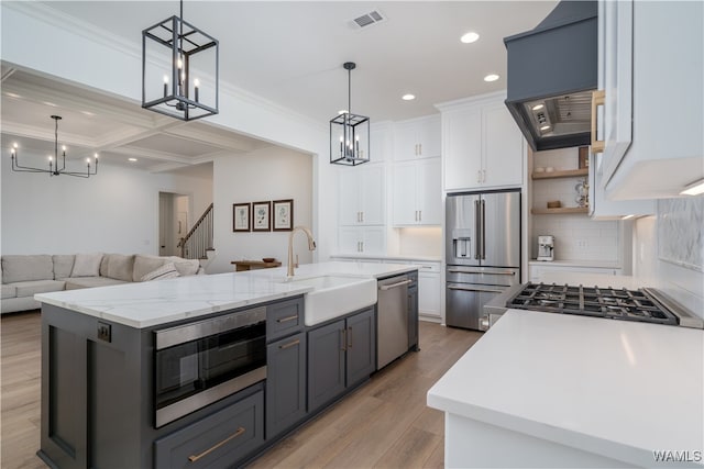 kitchen featuring a center island with sink, hanging light fixtures, light wood-type flooring, appliances with stainless steel finishes, and white cabinetry