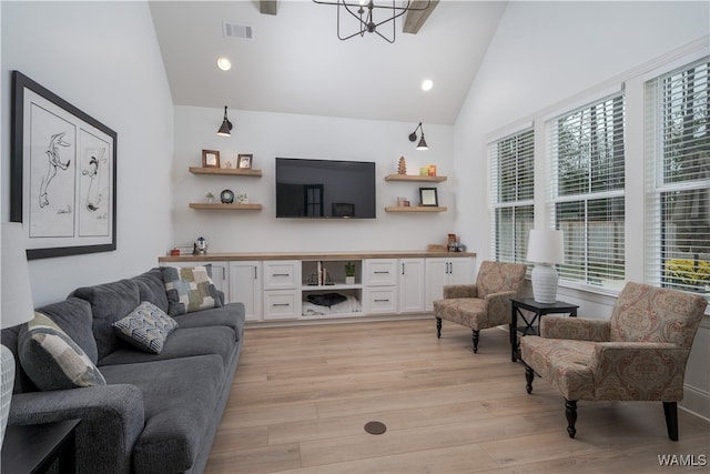 living room with a notable chandelier, high vaulted ceiling, light hardwood / wood-style floors, and a wealth of natural light