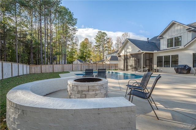 view of patio / terrace featuring pool water feature, a fire pit, grilling area, a sunroom, and a fenced in pool