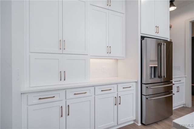 kitchen featuring white cabinetry, decorative backsplash, stainless steel fridge, and light hardwood / wood-style flooring