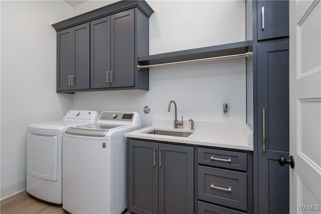 washroom featuring cabinets, independent washer and dryer, light wood-type flooring, and sink