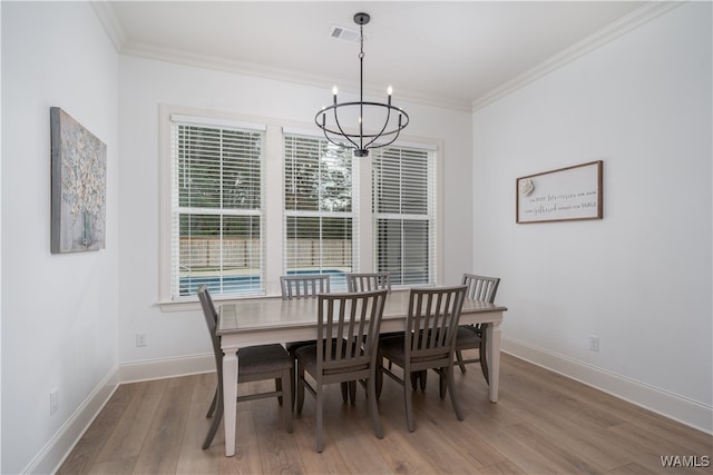 dining area with an inviting chandelier, crown molding, and light hardwood / wood-style flooring