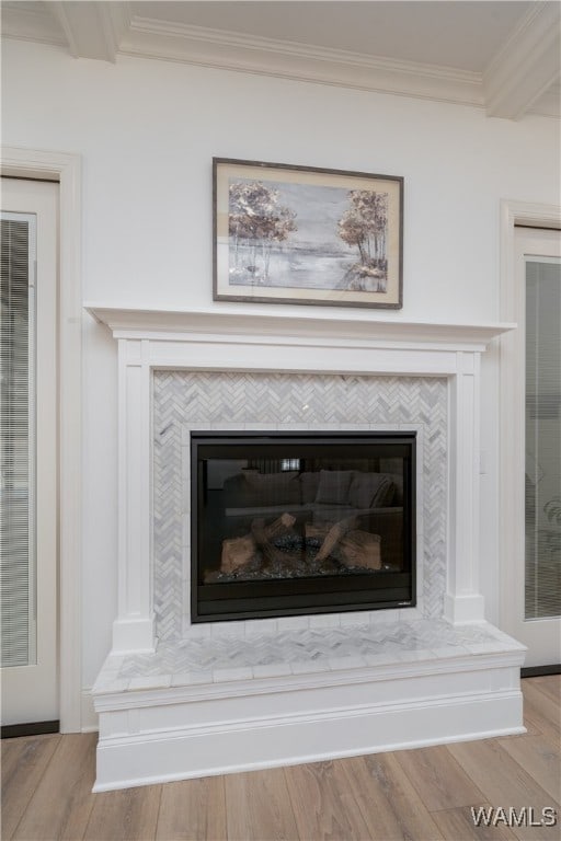 details with beamed ceiling, wood-type flooring, ornamental molding, and a tiled fireplace