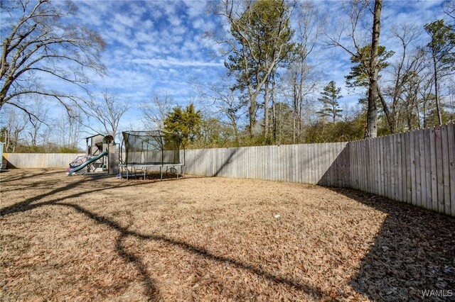 view of yard with a playground and a trampoline