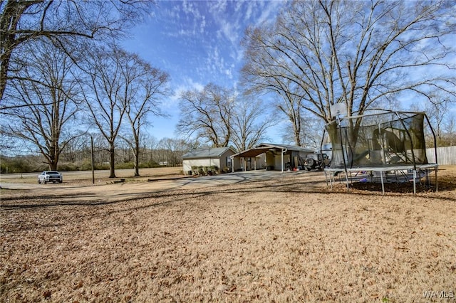 view of yard featuring a carport and a trampoline