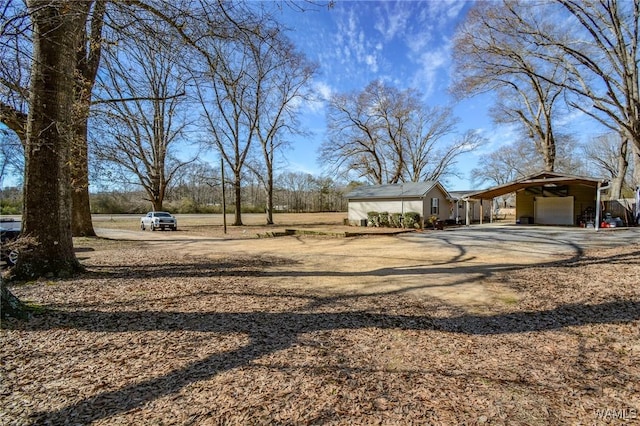 view of yard featuring a carport, a garage, and an outdoor structure