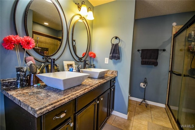 bathroom featuring walk in shower, vanity, tile patterned flooring, and a textured ceiling