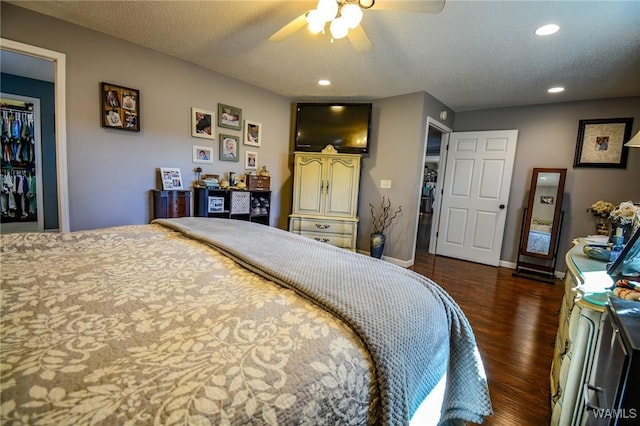 bedroom with ceiling fan, dark hardwood / wood-style floors, a textured ceiling, a walk in closet, and a closet