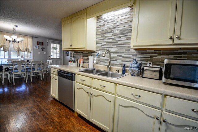 kitchen with pendant lighting, sink, appliances with stainless steel finishes, cream cabinets, and a textured ceiling