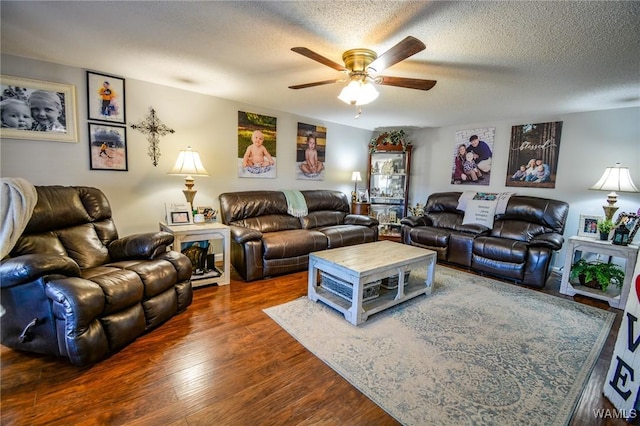 living room with ceiling fan, dark wood-type flooring, and a textured ceiling