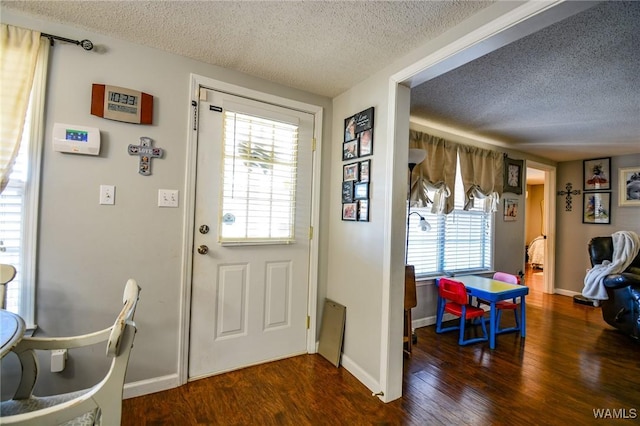 doorway with dark hardwood / wood-style floors and a textured ceiling