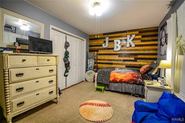 carpeted bedroom with wooden walls and a closet