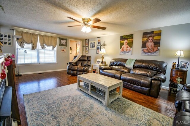 living room featuring ceiling fan, dark wood-type flooring, and a textured ceiling