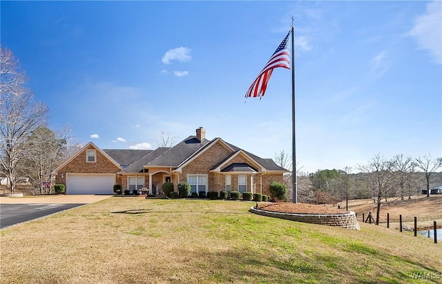 view of front of home with brick siding, a chimney, a front yard, a garage, and driveway