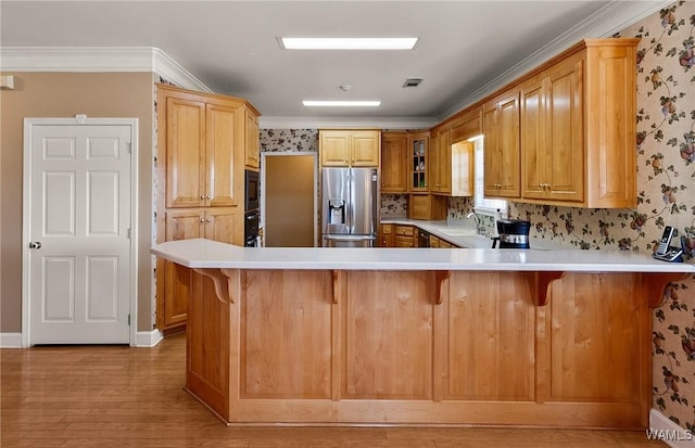 kitchen featuring crown molding, black appliances, a peninsula, and wallpapered walls