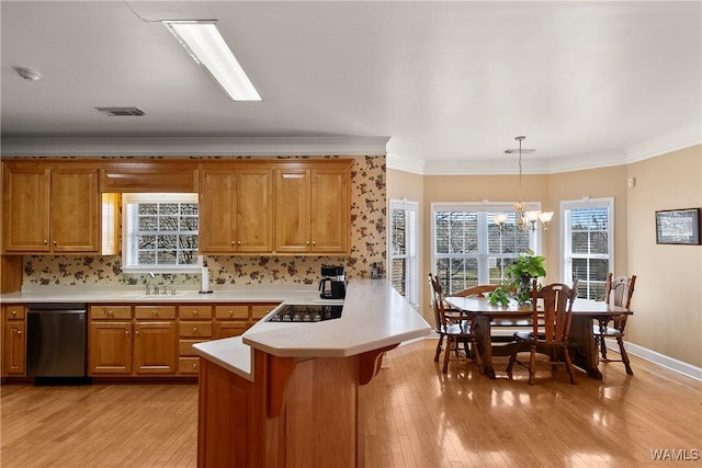 kitchen featuring light countertops, stainless steel dishwasher, brown cabinetry, stovetop, and a peninsula