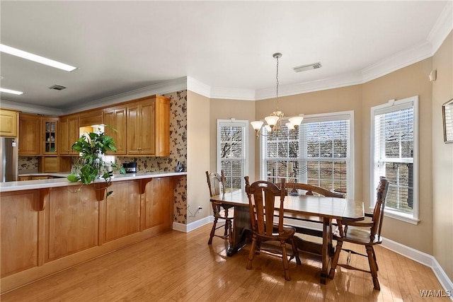 dining space with light wood-style floors, visible vents, ornamental molding, and an inviting chandelier