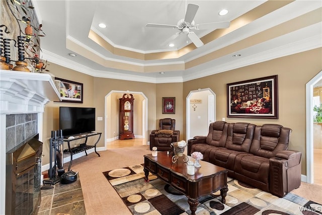 living area featuring arched walkways, a premium fireplace, baseboards, carpet, and a raised ceiling