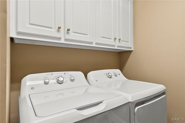 washroom featuring washing machine and clothes dryer and cabinet space