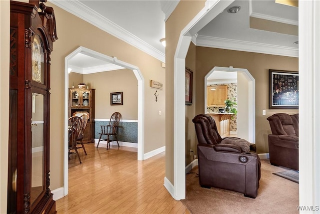 living area featuring ornamental molding, arched walkways, and light wood-style flooring