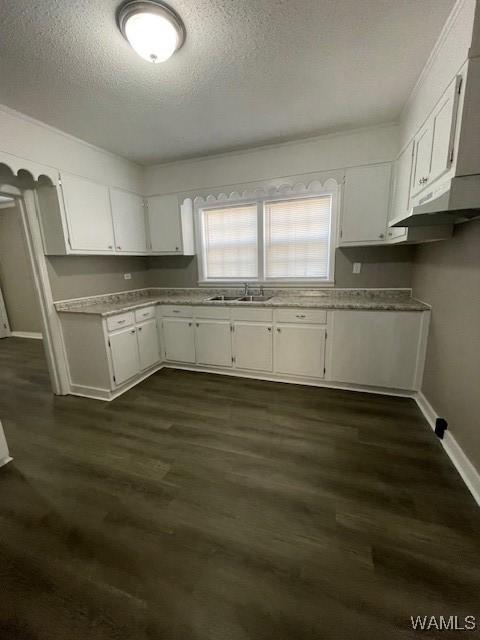 kitchen with baseboards, dark wood-style floors, light countertops, white cabinetry, and a sink