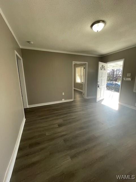 empty room with baseboards, ornamental molding, dark wood finished floors, and a textured ceiling