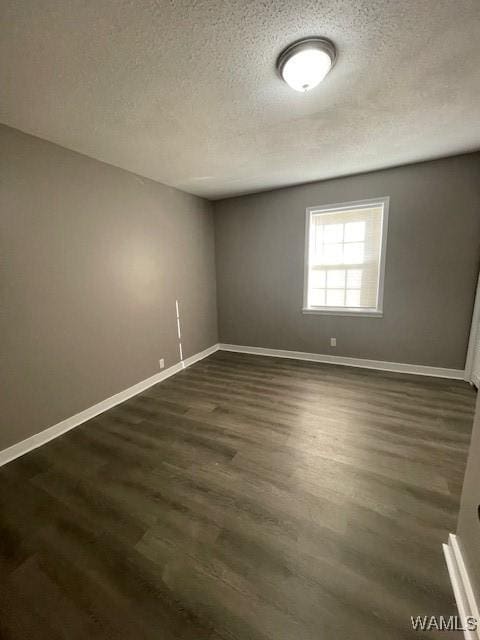 unfurnished room with a textured ceiling, dark wood-style flooring, and baseboards