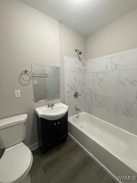 full bath featuring a textured ceiling, toilet, wood finished floors, vanity, and bathing tub / shower combination