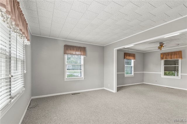 carpeted empty room featuring plenty of natural light, crown molding, and ceiling fan