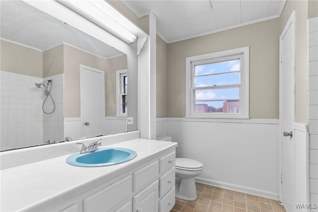 bathroom featuring vanity, toilet, ornamental molding, and a tile shower