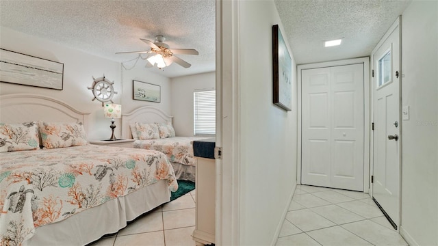 tiled bedroom featuring a closet, ceiling fan, and a textured ceiling