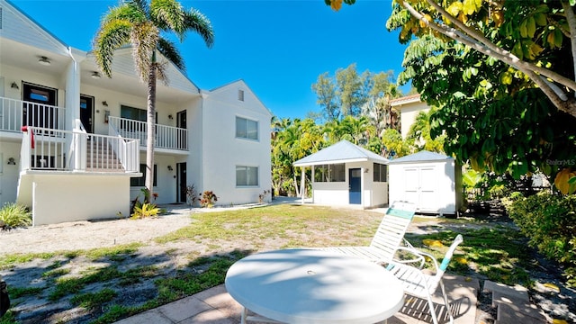 view of yard with a balcony, a storage unit, and a patio