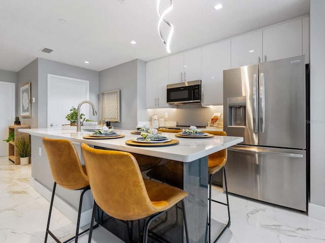 kitchen featuring a breakfast bar, white cabinetry, and appliances with stainless steel finishes