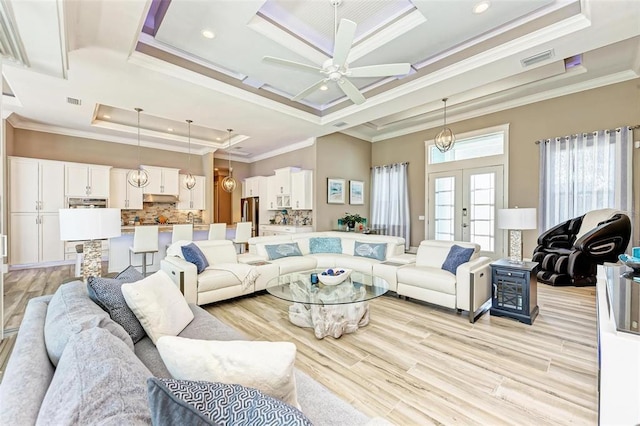 living room featuring a raised ceiling, crown molding, ceiling fan, and light wood-type flooring