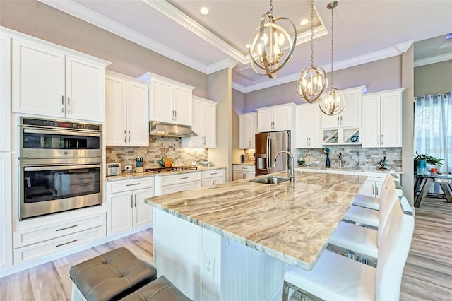 kitchen featuring a breakfast bar, sink, light hardwood / wood-style flooring, stainless steel appliances, and white cabinets