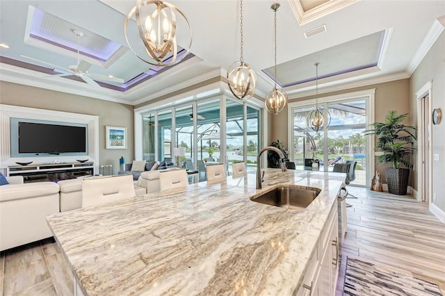 kitchen featuring sink, hanging light fixtures, white cabinets, light hardwood / wood-style floors, and ceiling fan with notable chandelier