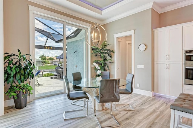 dining room featuring ornamental molding, a chandelier, a raised ceiling, and light hardwood / wood-style flooring