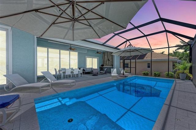 pool at dusk featuring ceiling fan, a patio, and a lanai