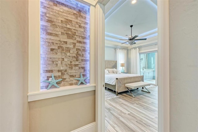 bedroom with a raised ceiling, light hardwood / wood-style floors, and crown molding