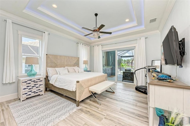 bedroom with a tray ceiling, light hardwood / wood-style floors, ceiling fan, and access to exterior