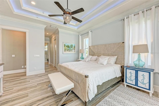 bedroom featuring ornamental molding, ceiling fan, a raised ceiling, and light hardwood / wood-style flooring