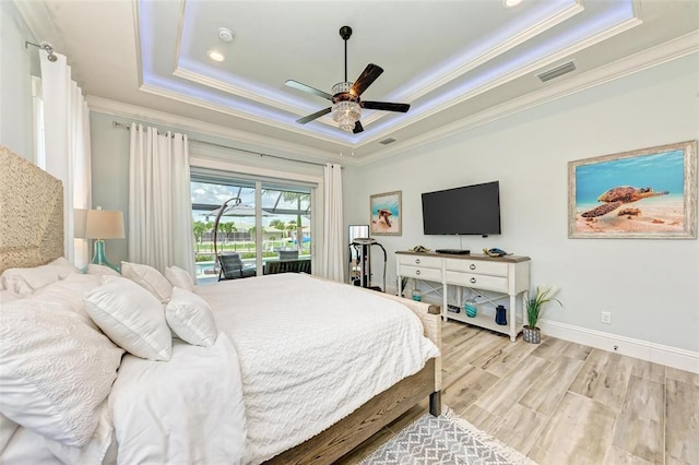 bedroom featuring ceiling fan, crown molding, a raised ceiling, and light wood-type flooring