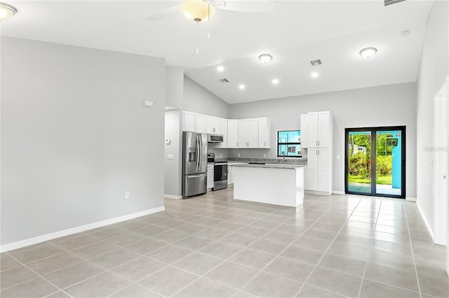 kitchen featuring light tile floors, a kitchen island, appliances with stainless steel finishes, white cabinets, and light stone countertops