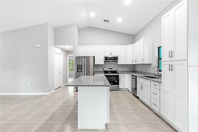 kitchen with stainless steel appliances, stone countertops, sink, and a center island