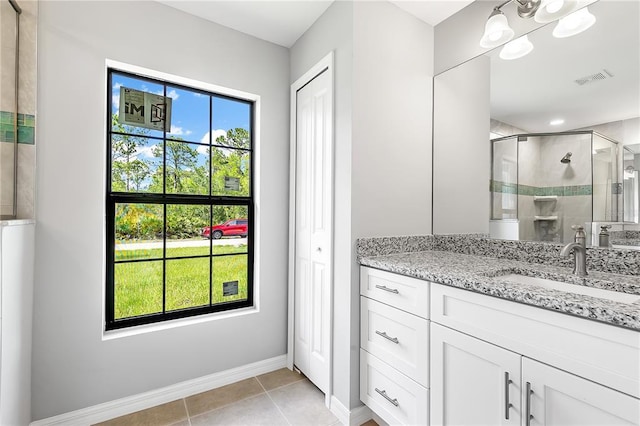 bathroom with an enclosed shower, vanity, tile floors, and a healthy amount of sunlight