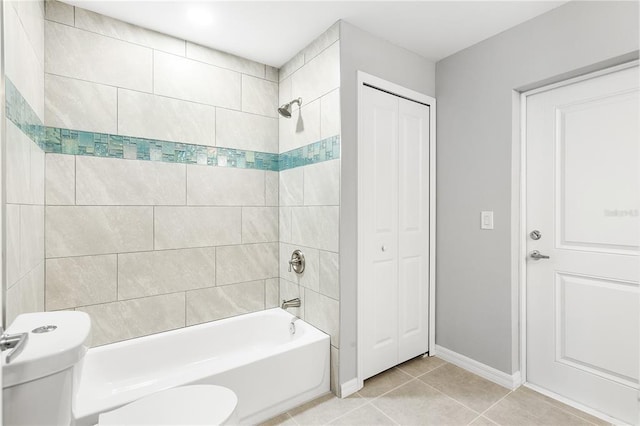 bathroom with toilet, tiled shower / bath, and tile flooring