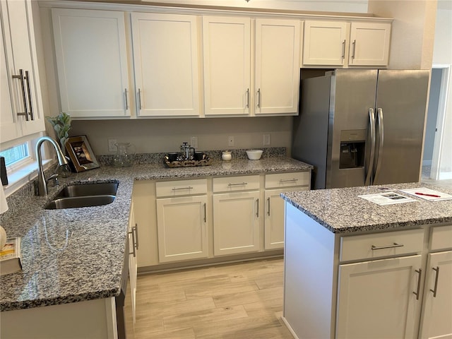 kitchen featuring stainless steel fridge with ice dispenser, sink, stone counters, and light hardwood / wood-style flooring