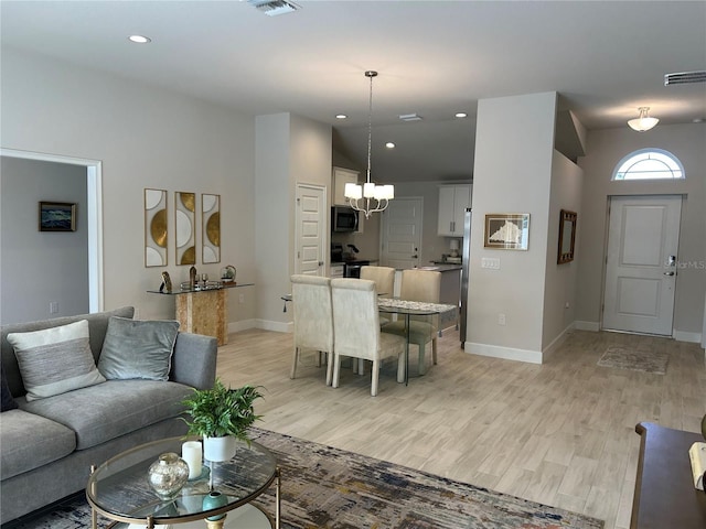 living room with light hardwood / wood-style floors, lofted ceiling, and a chandelier