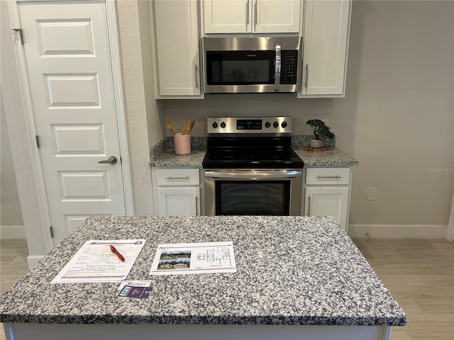 kitchen with white cabinets, light hardwood / wood-style floors, and stainless steel appliances